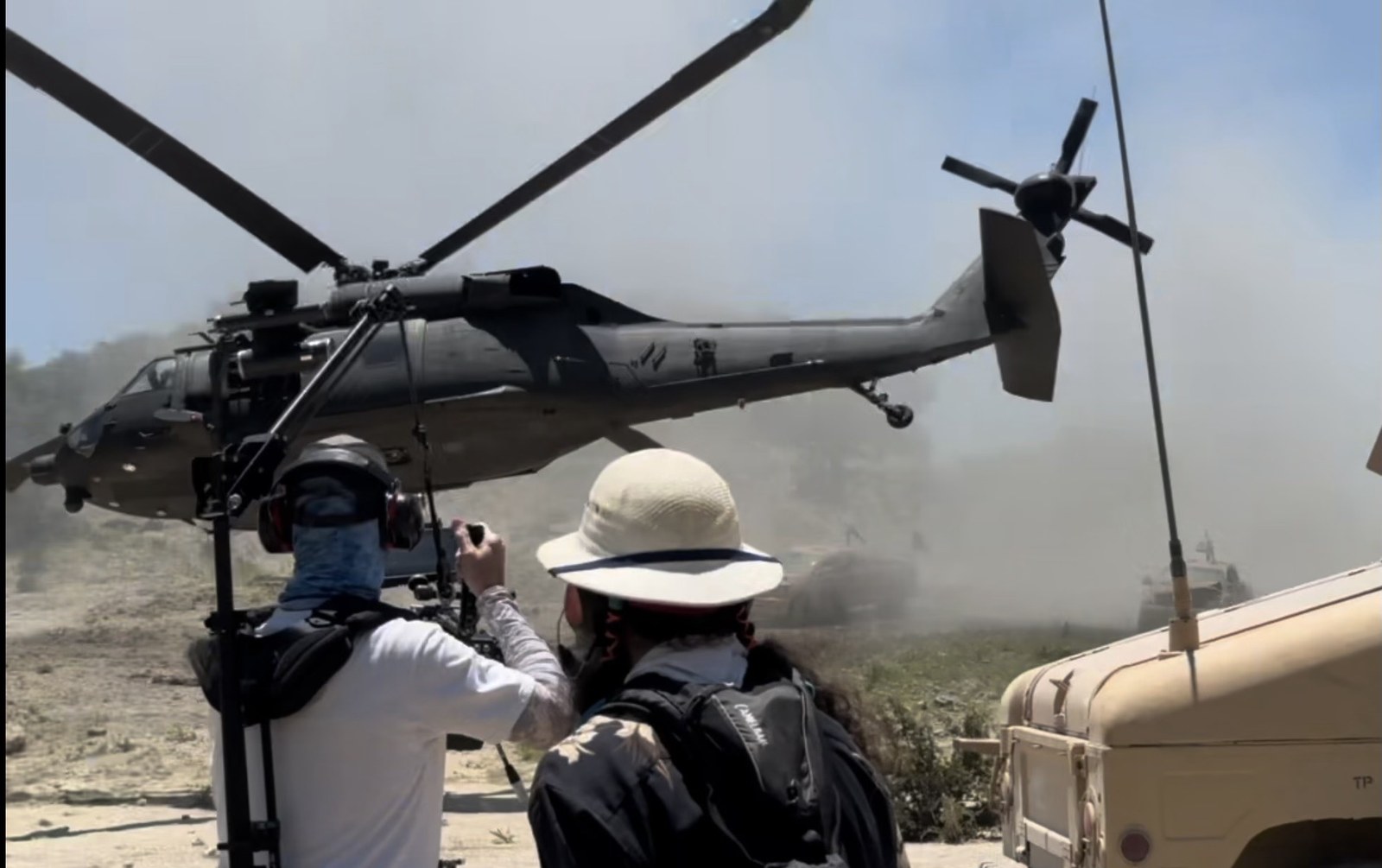 Military UH-60 Black Hawk helicopter hovering low in desert dust on set