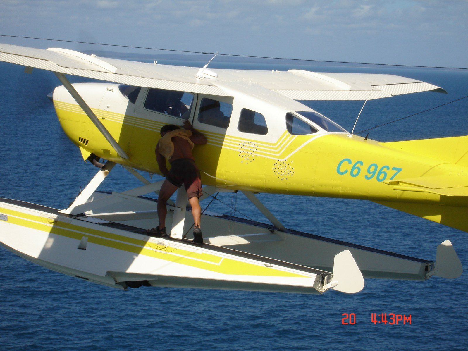 Stuntman hanging onto the wing strut of a yellow floatplane over the ocean